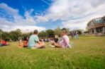 Several groups of students sitting and standing around the Green.