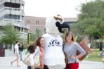 Ozzie Osprey stands with two female students on each side for a photo.