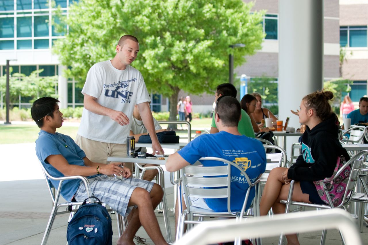 Three males and a female at a table talking.