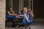 Three female students sitting on a picnic table singing and studying under the shelter of Honor Hall.