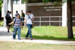 A female and male students walking and talking to each other in front of the John E. Mathews Jr. Building.