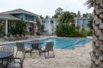 A building with a pool and tables and chairs sitting around.